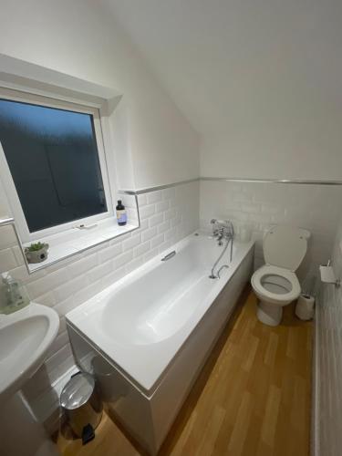 a bathroom with a tub and a toilet and a window at The Beach Loft in Newbiggin-by-the-Sea