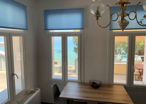 ein Esszimmer mit einem Holztisch und Fenstern in der Unterkunft Blue Flag Award Winning Beach: Home 2 in Vrontádos