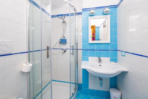 ein blau-weißes Bad mit einem Waschbecken und einer Dusche in der Unterkunft La Mansardina dell'Agrumeto in Vico Equense