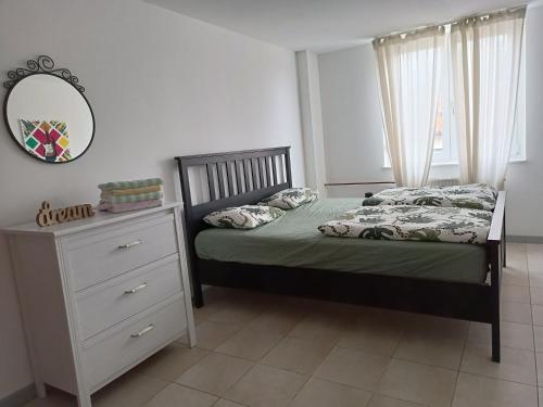 Schlafzimmer mit einem Bett, einer Kommode und einem Spiegel in der Unterkunft Apartma 31 in Nova Gorica