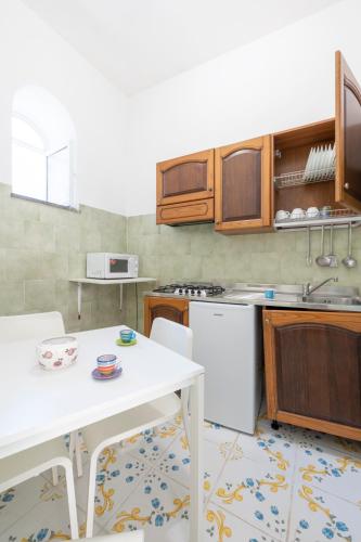 a kitchen with wooden cabinets and a white table at Villaggio Residence Nettuno in Massa Lubrense