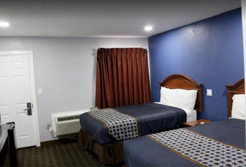 Habitación de hotel con 2 camas y pared azul en Economy Inn, en Ada