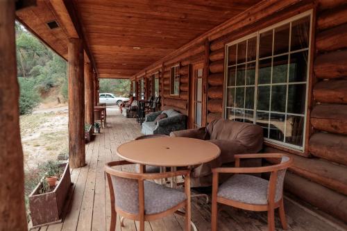 a porch of a log cabin with a table and chairs at Bear Creek Cabins in Midpines