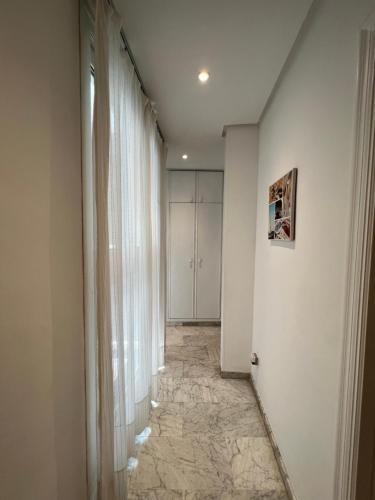 un pasillo con paredes y cortinas blancas y suelo de baldosa en Iberflat Fabiola en Sevilla