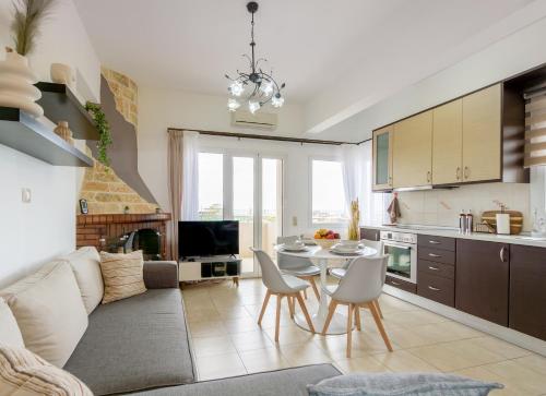 ヘルソニソスにあるΝΜΒ Anissaras Coastal Getawayのテーブルと椅子のあるキッチンとリビングルーム