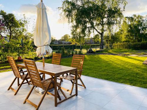 a wooden table with chairs and an umbrella at HORAMI Villa - ORIGAMI Apartment mit Terrasse in Malchow