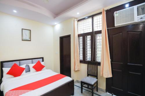 a bedroom with a bed with red pillows and a window at OYO Golden Suites in Ghaziabad