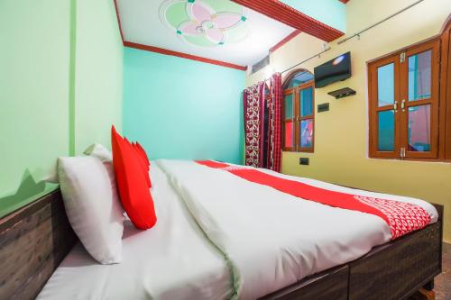 a bedroom with a bed with red and white pillows at OYO 66014 The Rudralok Hotel in Gopeshwar