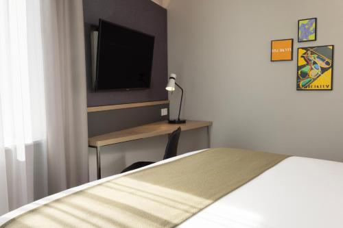 a bedroom with a bed and a desk with a television at Holiday Inn - Eindhoven Airport by IHG in Eindhoven