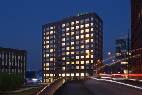 埃因霍溫的住宿－Holiday Inn - Eindhoven Airport, an IHG Hotel，城市街道上一座高大的建筑,有明亮的窗户