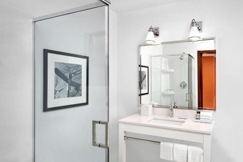 W łazience znajduje się umywalka i lustro. w obiekcie Grand Park Hotel Vancouver Airport w mieście Richmond
