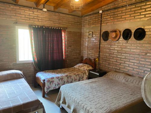 1 dormitorio con 2 camas y pared de ladrillo en Cabaña Las Calandrias in 