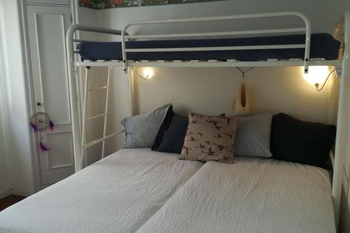 1 dormitorio con litera con sábanas y almohadas blancas en Acogedor apartamento a pie de playa, en Nigrán