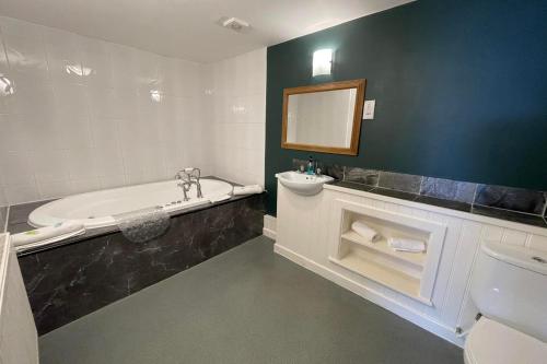 ein Badezimmer mit einer Badewanne, einem Waschbecken und einem Spiegel in der Unterkunft The Gardeners Country Inn in Goxhill