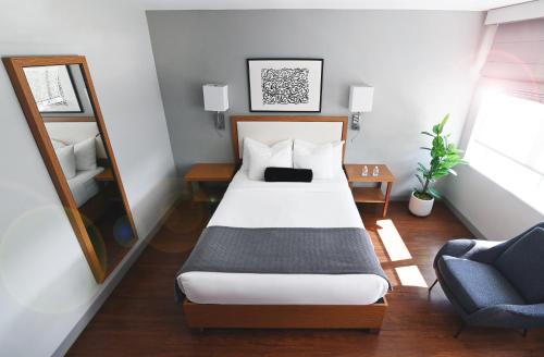 a bedroom with a bed and a mirror and a chair at Edge Hotel Washington Heights in New York