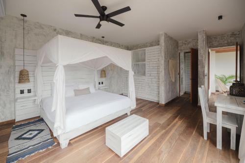 a bedroom with a white bed with a ceiling fan at Kai Tulum in Tulum