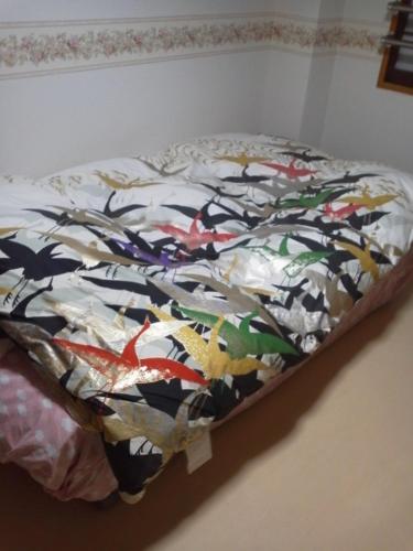 a bed with a comforter on top of it at Mizubasho in Takizawa