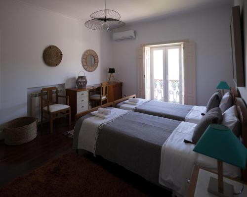 a bedroom with two beds and a desk and a window at Casa Da Palmeira in Leiria