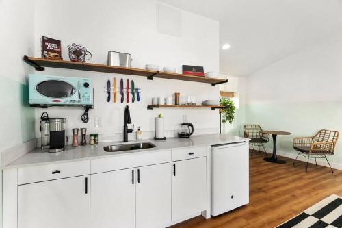 a white kitchen with a sink and a microwave at Mokuoeo Studio suite.nui in Chandler