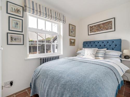 a bedroom with a blue bed and a window at Old Rectory Cottage in Fernhurst