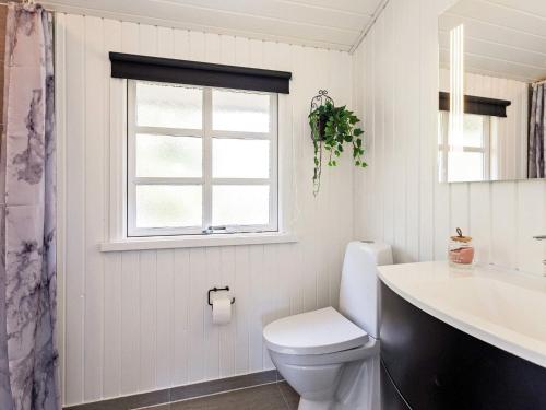 La salle de bains est pourvue de toilettes, d'un lavabo et d'une fenêtre. dans l'établissement Holiday home Løkken CLXIX, à Løkken