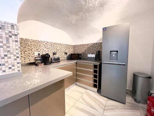 a kitchen with white counters and a refrigerator at The Beverley Apartments London - Victoria in London