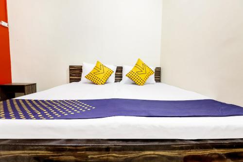 a bed with yellow and purple pillows on it at Hotel O Tirupati Guest House in Gwalior