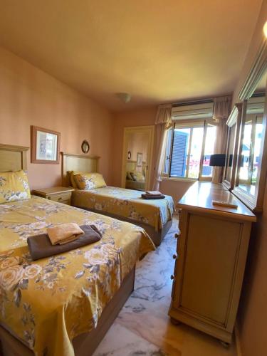 - une chambre avec 2 lits, une table et des fenêtres dans l'établissement Beachfront Apartment CALAHONDA BEACH, à Sitio de Calahonda
