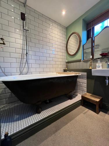 baño con bañera negra grande y espejo en The Writers Cottage - Intriguing & Romantic, en Holmfirth