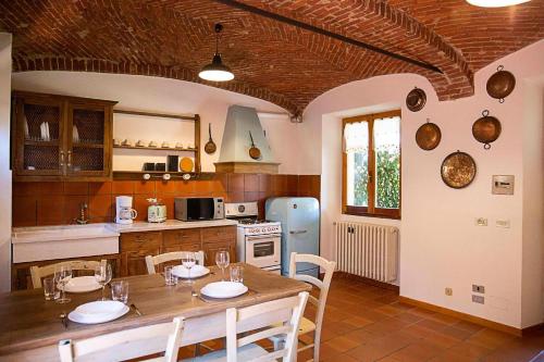 uma cozinha com uma mesa e cadeiras e um frigorífico em LE ORTENSIE - Holiday country house em Pisano