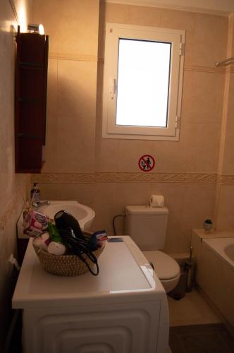 a bathroom with a sink and a toilet and a window at Blue and White in Schinias