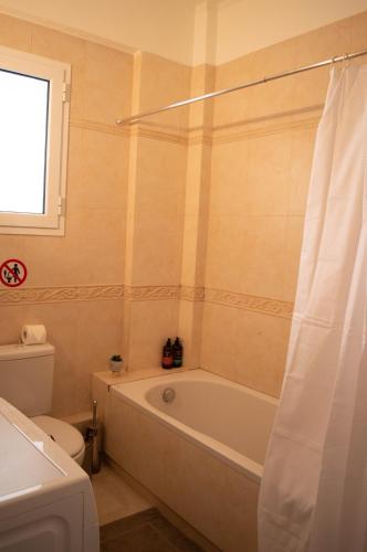a bathroom with a bath tub and a toilet at Blue and White in Schinias