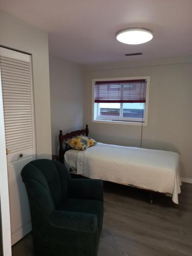 a bedroom with a bed and a chair and a window at Green&White House in Coquitlam