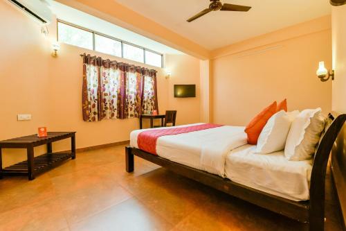 1 dormitorio con cama, mesa y ventana en OYO 13415 Cherai Village Home Stay en Cherai Beach