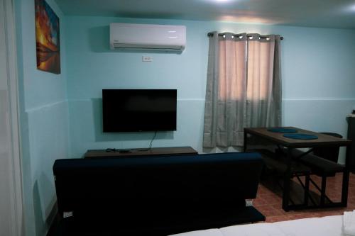 a living room with a flat screen tv and a table at MAVS COMBATE BEACH CLUB in Cabo Rojo