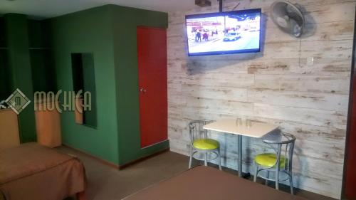 a room with a table and a tv on a wall at Hostal Residencial Mochica in Lima