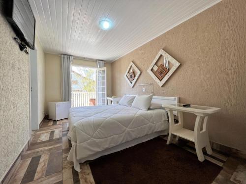 a bedroom with a bed and a table and a window at Hotel Solar da Montanha in Campos do Jordão