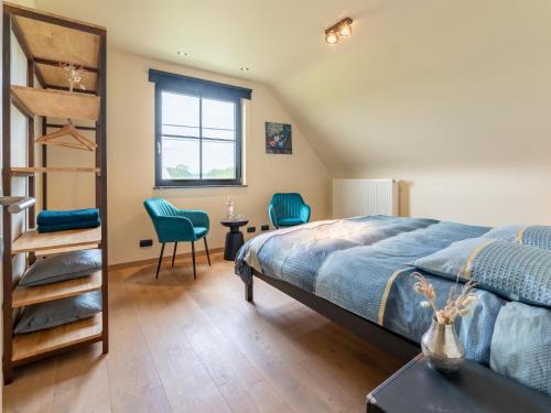 een slaapkamer met een bed en twee blauwe stoelen bij Villa Meersen in Maldegem