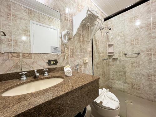 a bathroom with a sink and a toilet and a mirror at Hotel Solar da Montanha in Campos do Jordão