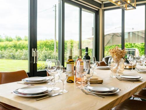 a long wooden table with glasses and wine bottles at Landgoed Meersen in Maldegem