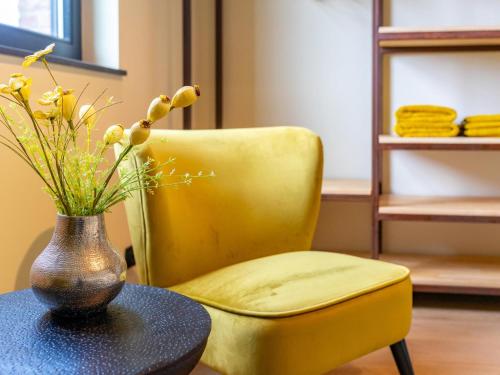a yellow chair and a table with a vase of flowers at Landgoed Meersen in Maldegem
