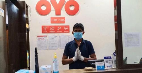 a man wearing a mask standing in front of a store at OYO 66982 Hotel Skyway Inn in Mumbai