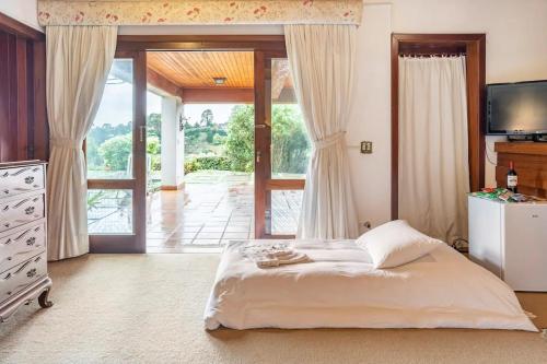 1 dormitorio con 1 cama y puerta corredera de cristal en Suites no Alto do Capivari, en Campos do Jordão