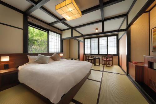 1 dormitorio con 1 cama blanca grande y ventanas en Zao Onsen Omiya Ryokan, en Zao Onsen