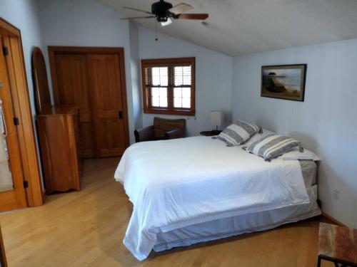 1 dormitorio con cama blanca y ventilador de techo en Lake Front Heated Floors Hot Tub Firepit Secluded, en Eldred