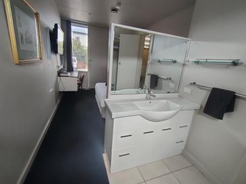 Baño blanco con lavabo y espejo en International Hotel Motel en Port Pirie