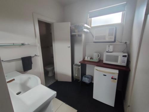baño pequeño con fregadero y microondas en International Hotel Motel en Port Pirie