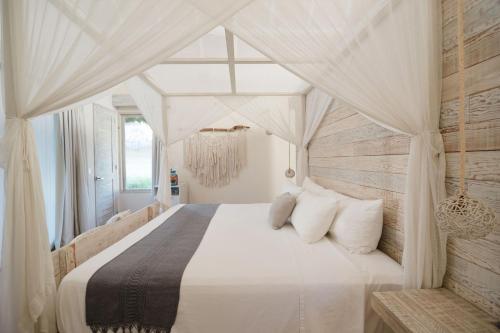 a bedroom with a canopy bed with white sheets and pillows at Kai Tulum in Tulum