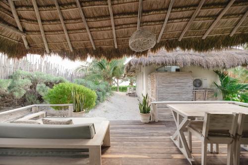 a patio with two beds and a table and a hut at Kai Tulum in Tulum