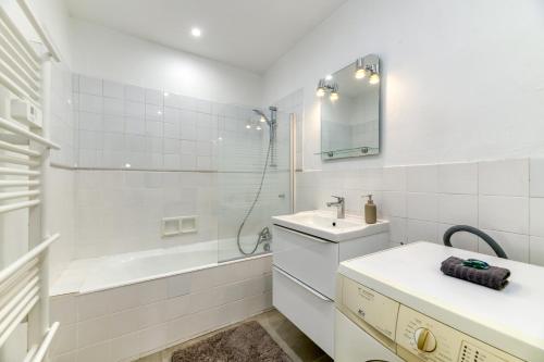 une salle de bain blanche avec un lavabo et une baignoire dans l'établissement Le Prestige•Gare•Cours Jean Jaurès•Confort•Netflix, à Grenoble